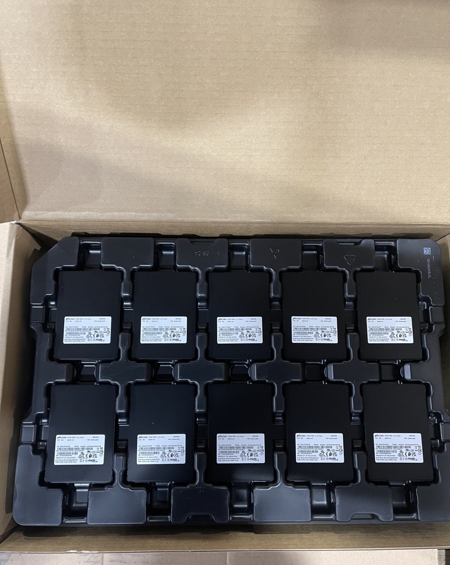 Ten new Micron 7450 PRO U.3 SSDs in a factory shipping tray inside the carton